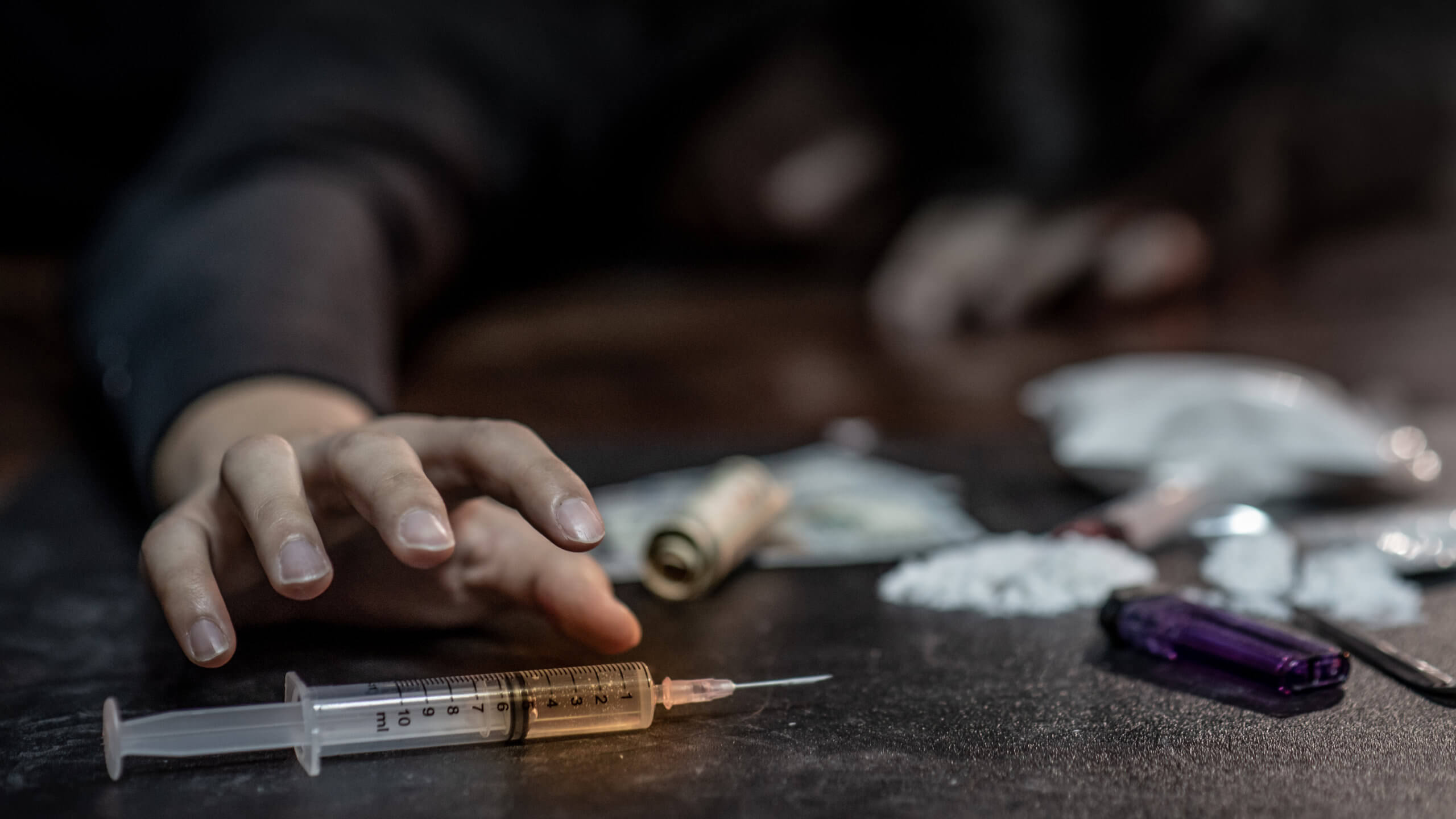 An image of prescription pills and a syringe representing drug addiction